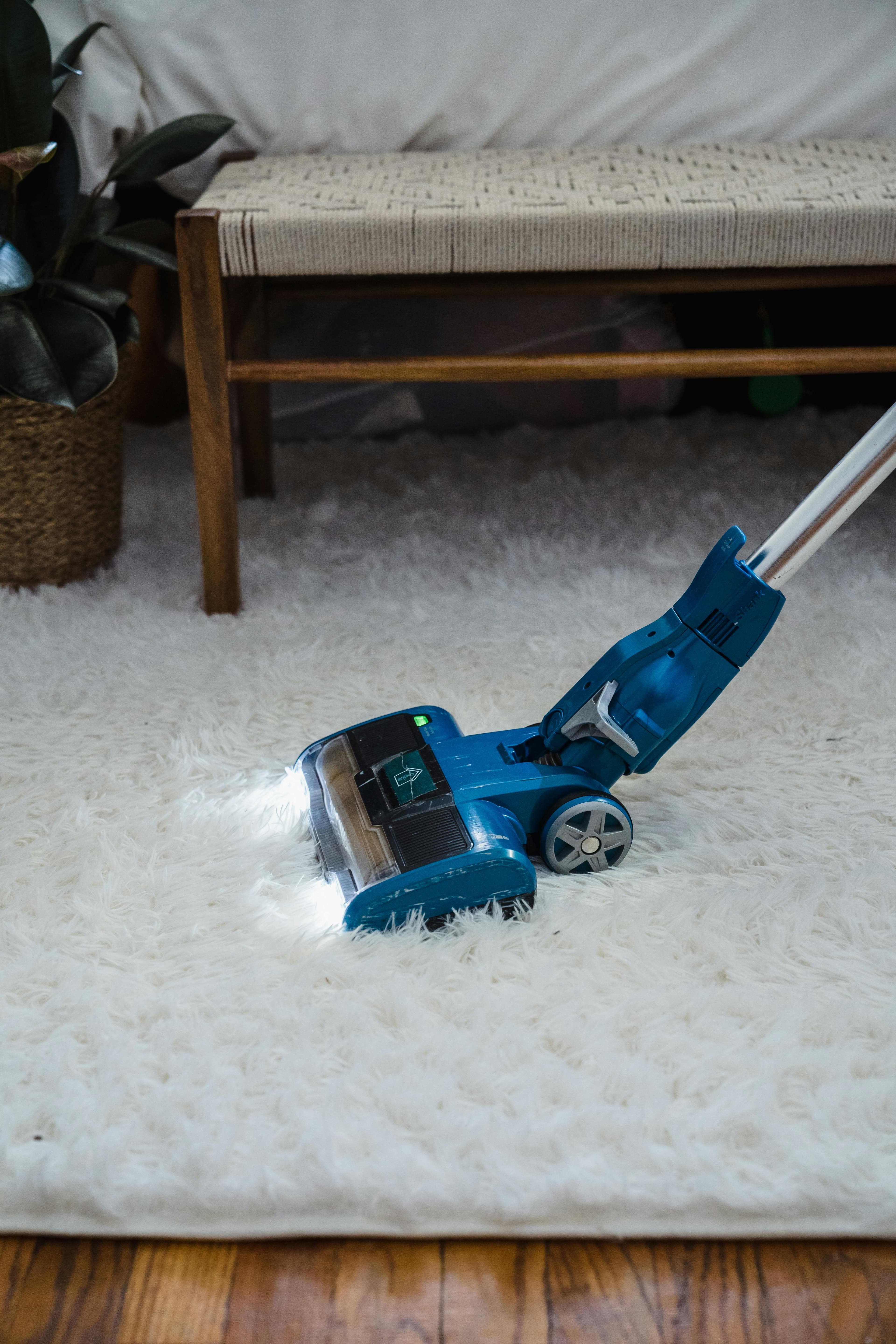 blue vacumm cleaner cleaning a white carpet